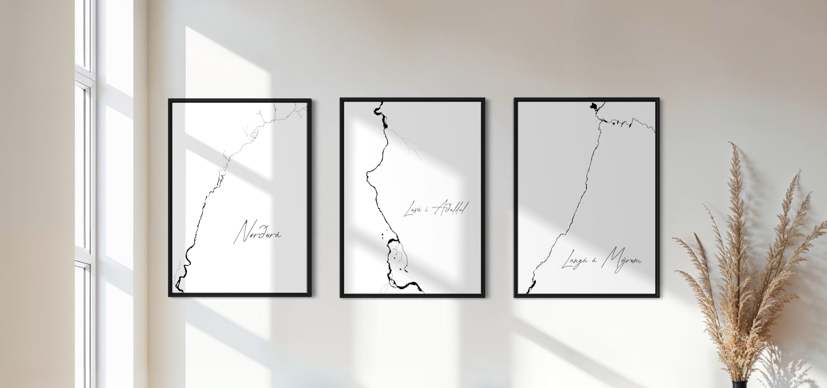Three framed black and white artworks on a wall with a bench and vase in the foreground.